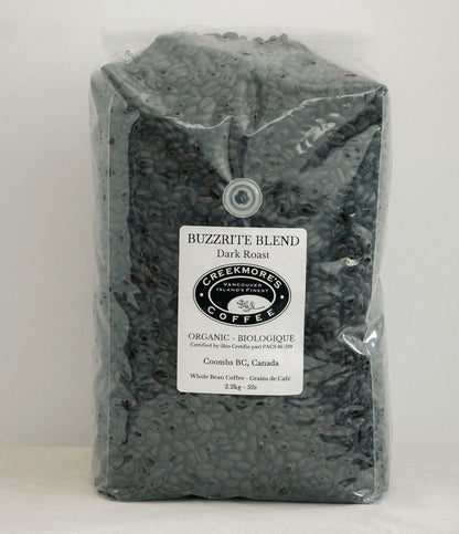 A 23kg bag of Creekmore's 'Buzzrite Blend' organic dark roast coffee, shown in a clear plastic bag with a white label on a light gray background.