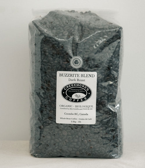 A 23kg bag of Creekmore's 'Buzzrite Blend' organic dark roast coffee, shown in a clear plastic bag with a white label on a light gray background.